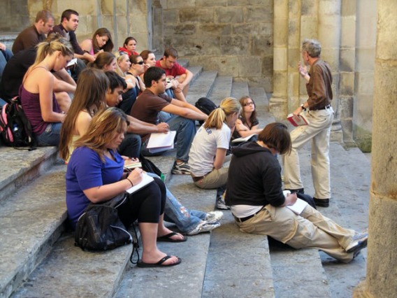 Students sitting on city steps listening to professor