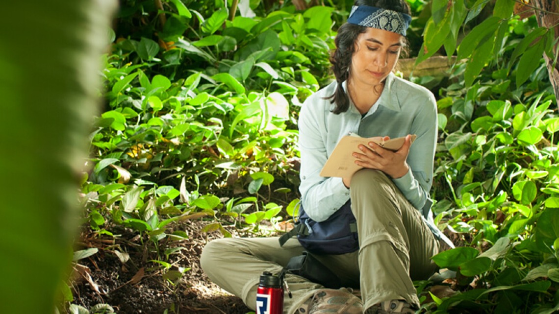 Girl seated in jungle area taking notes